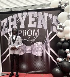 a man standing in front of a black and white backdrop that says hyven's prom and off