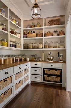 a kitchen with lots of white cabinets and wooden flooring on both sides of the shelves