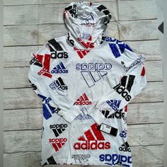 New With Tags Is A Long Sleeve T-Shirt With Sketchy Adidas Logos. - Size Large (14/16) - 100% Cotton Casual Hooded Top With Graphic Print, Spring Logo Print Hoodie, Sports Graphic Print Hoodie Top, Athletic Graphic Print Hoodie Top, Casual Hoodie Tops With Logo Print, White Hooded Top For Spring, Sporty Long Sleeve Hoodie With Graphic Print, White Graphic Print Hooded Top, White Hooded Top With Graphic Print