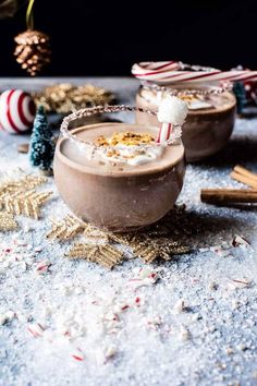 two glasses filled with hot chocolate and marshmallows on top of a table