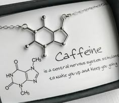 a necklace with caffeine written on it is displayed in a black box next to a card