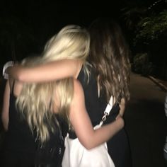 two women hugging each other outside at night