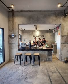 three stools in front of a counter with people sitting at it