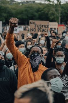 a man wearing a face mask holds up his fist as he stands in front of a crowd