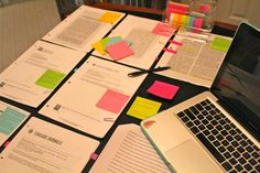 a laptop computer sitting on top of a table covered in papers and sticky notes,