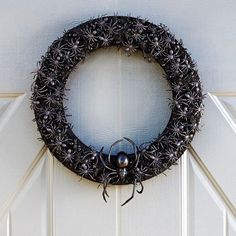 a black wreath with spider webs hanging from it's side on a white door