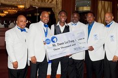 a group of men in white suits holding a large check