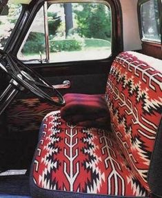 the interior of an old car with red and black patterned upholstered seat covers