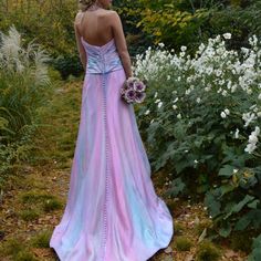 a woman in a pink and blue dress standing next to flowers