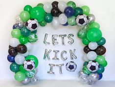 a balloon arch that says let's kick it with soccer balls and streamers