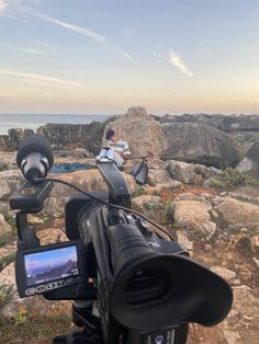 a camera is set up on the rocks by the ocean to take pictures and videos