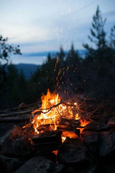 a campfire is lit up in the dark with lots of sparks coming from it