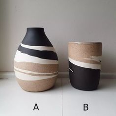 two black and white vases sitting next to each other on a table with letters below them