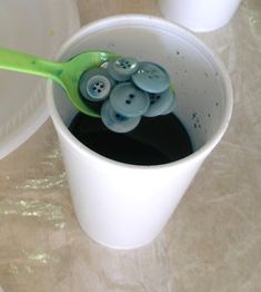 a cup filled with buttons and a green spoon