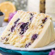 a slice of cake on a plate with blueberries and lemons in the background