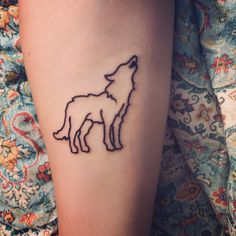 a tattoo on the leg of a woman with two wolf silhouettes in front of her