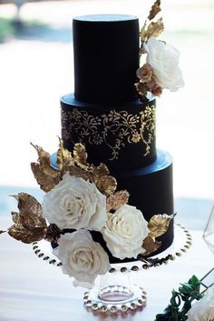 a black and gold wedding cake with white flowers