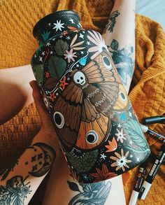 a person with tattoos on their arms holding a vase