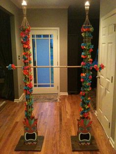 two tall metal poles with flowers on them in front of a door and another one standing next to it