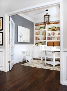 an open door leading to a white desk and bookshelf in a home office