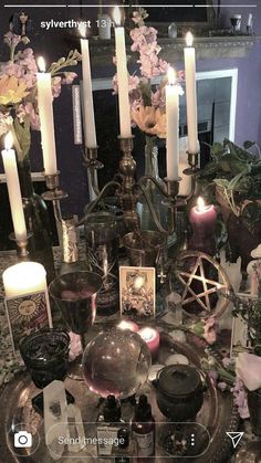 a table topped with lots of candles next to flowers and other things on top of it