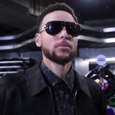 a man wearing sunglasses and a leather jacket in a parking garage with his hand on his hip