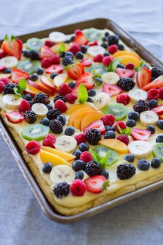 a fruit tart with blueberries, raspberries and mint leaves on top