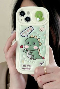 a woman holding up a cell phone case with an image of a dinosaur on it