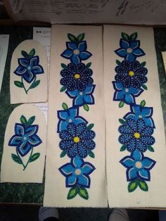 four pieces of cloth with blue flowers and leaves on them, sitting next to each other