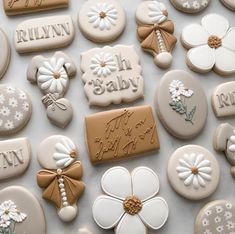 many decorated cookies are arranged on a table with the words baby spelled in white and brown