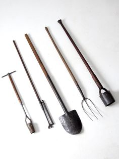 five different types of garden tools lined up on a white surface with one shovel, two rake and three other implements