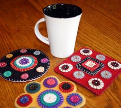 two coasters and a coffee cup on a table with a mug in the middle