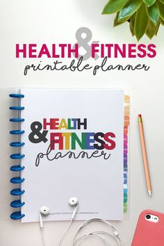 the health and fitness planner with headphones on it next to a phone, notebook, pencil