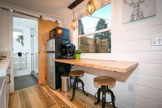 a small kitchen with two stools next to the counter and a coffee maker on the wall