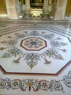 an intricately designed floor in the middle of a room with gold and white decor