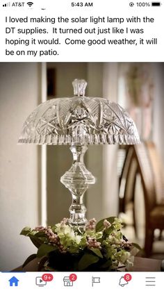 a glass lamp sitting on top of a table next to a vase filled with flowers