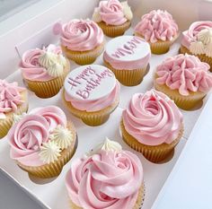 a box filled with pink frosted cupcakes on top of a white table