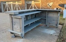 an outdoor kitchen made out of pallets and wooden planks is shown in front of a brick building