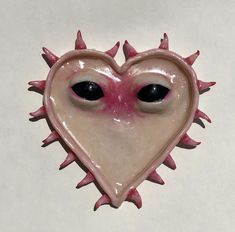 a pink heart shaped object with spikes on it's sides and two eyes in the shape of a heart