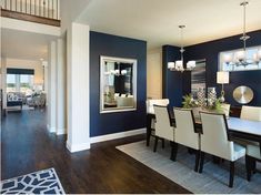 a dinning room with blue walls and white chairs is pictured in this image, it has hardwood flooring and dark wood floors