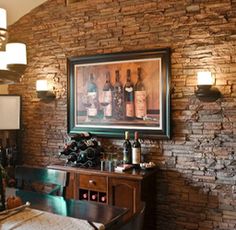 a dining room table with wine bottles on the wall and lights hanging from the ceiling