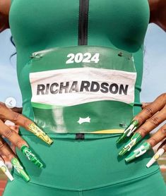 a woman with her hands on her hips wearing green and white running clothes that read richardson