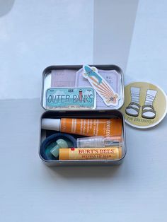 an open tin with some items in it on a white table next to a coin