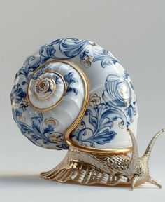 a blue and white snail figurine sitting on top of a gold plated base