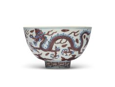 a white bowl with blue and brown designs on it's sides, in the shape of a dragon