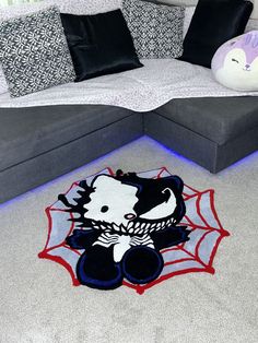 a living room area with a couch, rug and stuffed animal on the floor in front of it