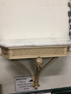 a white marble shelf with an ornate design on it's sides and a mirror behind it