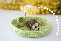 a crocheted basket with a small hedge on it and a flower in the middle