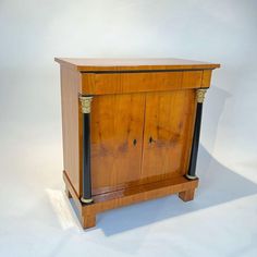 an old wooden cabinet with black handles and gold trimmings on the front, against a white background