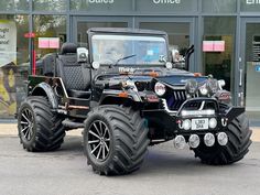 a black jeep with huge tires parked in front of a building